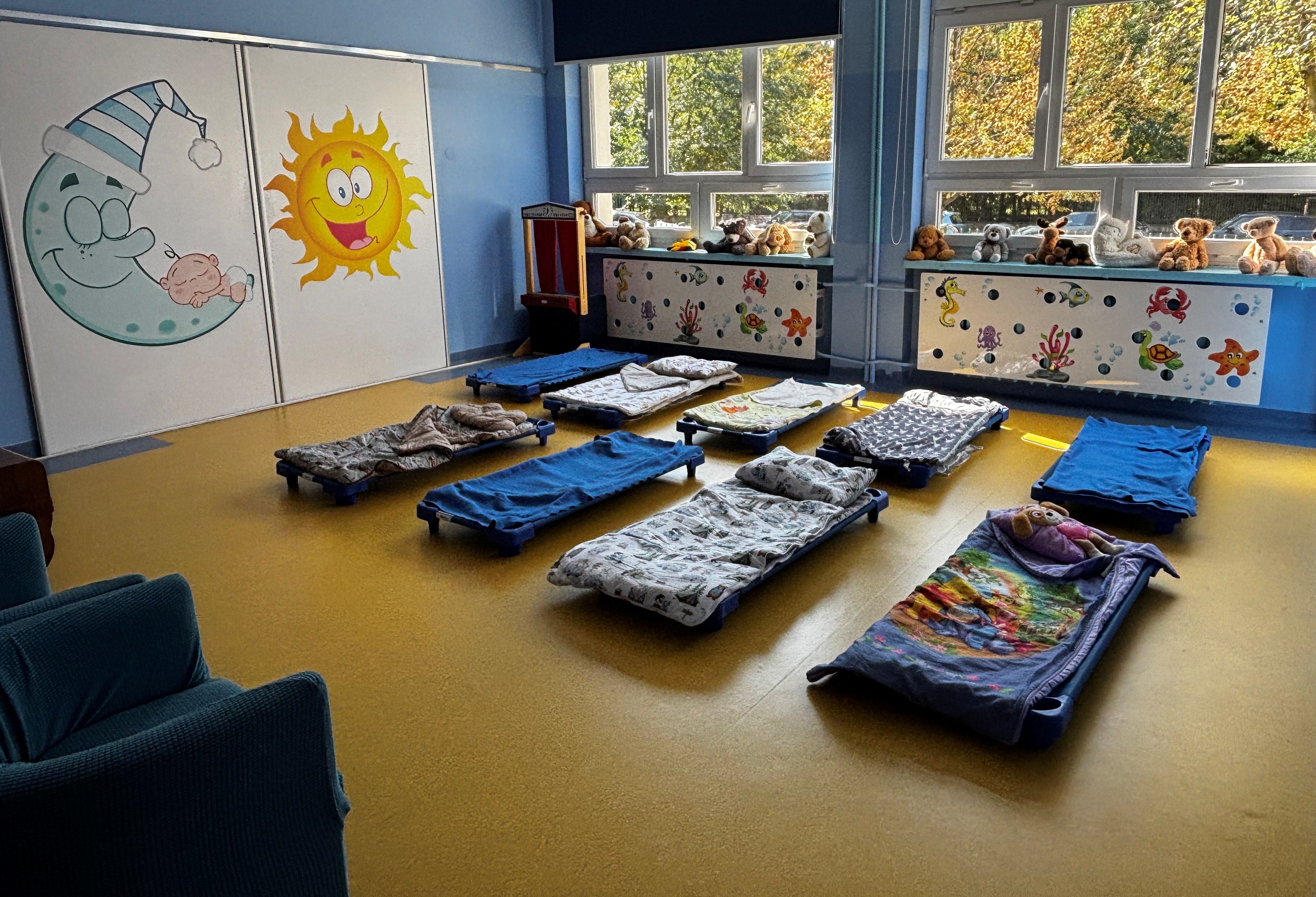 Sypialnia maluszków z leżakami z kolorową pościelą. 