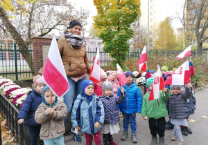 Dzieci maszerują z flagami do miejsca pamięci narodowej.