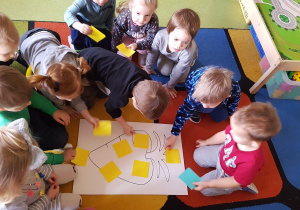 Dzieci z okazji Dnia Marchewki układają jej kształt z kolorowych kartoników.