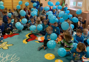Dzieci machają niebieskimi balonami.