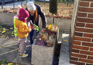 Chłopiec i dziewczynka składają kwiaty w Miejscu Pamięci Narodowej.