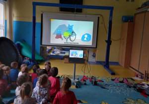Dzieci oglądają na dużym ekranie film o prawach dziecka.