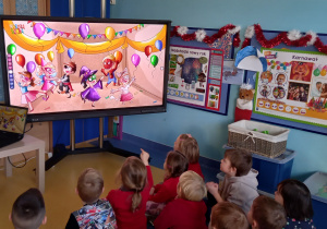 Dzieci oglądają na dużym ekranie prezentacje o karnawale.