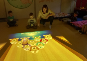 Magiczny dywan. Dzieci grają w multimedialne kręgle.