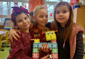 Dziewczynki pokazują wspólnie wykonaną konstrukcję z klocków.