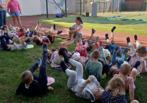 Tydzień olimpijski. Dzieci wykonują rozgrzewkę sportową na boisku szkolnym.