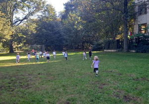 Tydzień olimpijski. Dzieci biegną do mety na trawiastym boisku w parku.