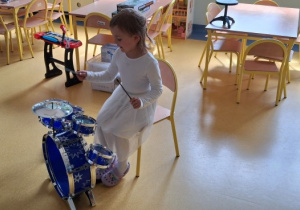 Dziewczynka gra na zabawkowej perkusji.