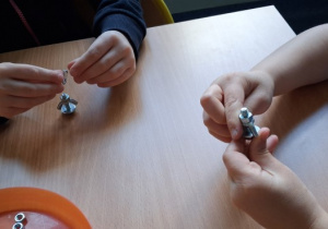 Dzieci nakręcają nakrętki na śrubki, tworząc prezent dla taty - ludzika breloczek.