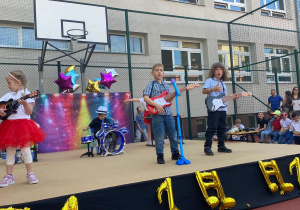 Występ z okazji Dnia Mamy i Taty "Koncert życzeń". Dzieci grają i śpiewają na scenie.