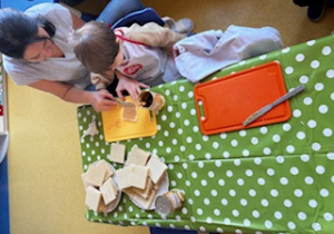 Dzieci smarują wafelki maską kajmakową.