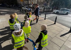 Dzieci stoją na chodniku i oglądają znaki drogowe.
