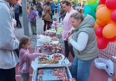 Rodzice i dzieci częstują się deserami, sokami i ciastem.