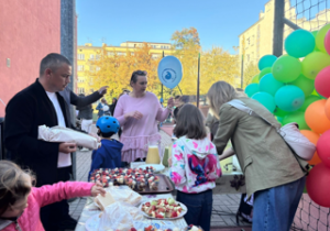 Na zdjęciu jedna z mam rozdaje balony dzieciom.