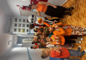 Dzieci pozują do zdjęcia z balonowym kościotrupem i panią nauczycielką.