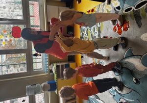 Dzieci podają sobie dynie nad głową.