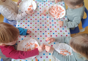 Dzieci kolorują szablon dyni.