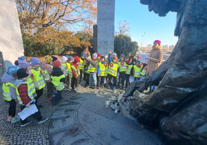 Dzieci stoją pod pomnikiem Sapera.