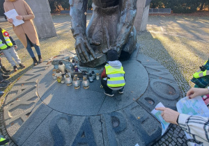 Chłopiec składa znicz pod pomnkiem.