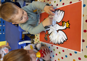 Chłopiec przykleja pióra orłowi.