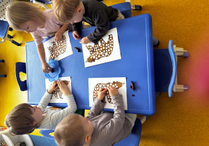 Dzieci wyklejają niedźwiedzia.