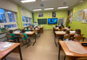 Eksperymenty w szkole, dzieci siedzą w ławkach i słuchają