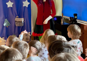 Pomocniczka Mikołaja pokazuje dzieciom gesty do naśladowania.