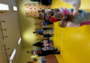 Dzieci stoją w pólkolu i słuchają dźwięków instrumentów.